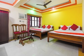 A hotel room with two beds, a ceiling fan, a window with curtains, and a chair.