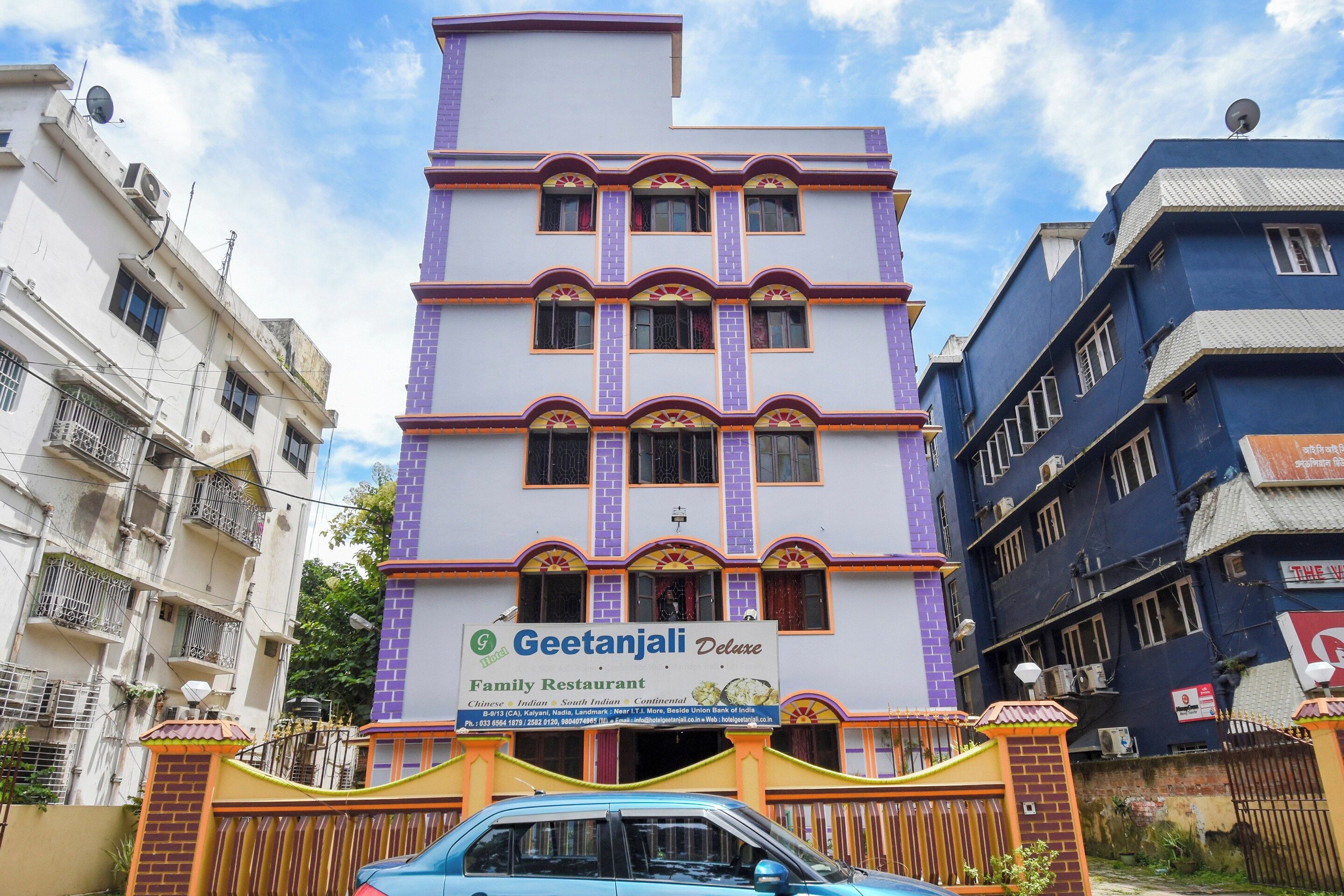 Un hotel de varios pisos con un letrero destacado para el Restaurante Familiar Geetanjali Deluxe.