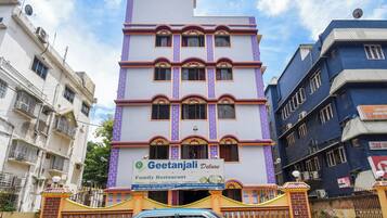 Un hotel de varios pisos con un letrero destacado para el Restaurante Familiar Geetanjali Deluxe.