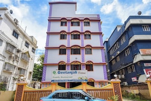 Um hotel com vários andares e um letreiro chamativo para o Geetanjali Deluxe Family Restaurant.