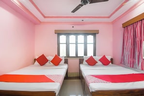 Una habitación con dos camas, un ventanal y un ventilador de techo.