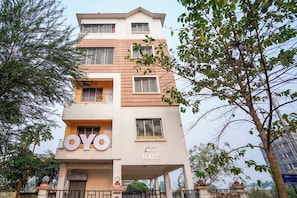 Un edificio de varios pisos con un letrero que dice 'OYO BEST HOUSE' y el número 'AA1253' visible.