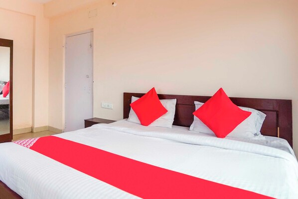 A hotel room with a bed, a nightstand, and a door.
