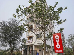 A multi-story building with a sign for 'OYO Urban Village Guest House' and a large red sign with the number '63847'.