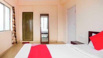 A hotel room with a bed, a wardrobe, a mirror, and a window.