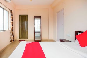 Ett hotellrum med en säng, en garderob, en spegel och ett fönster.