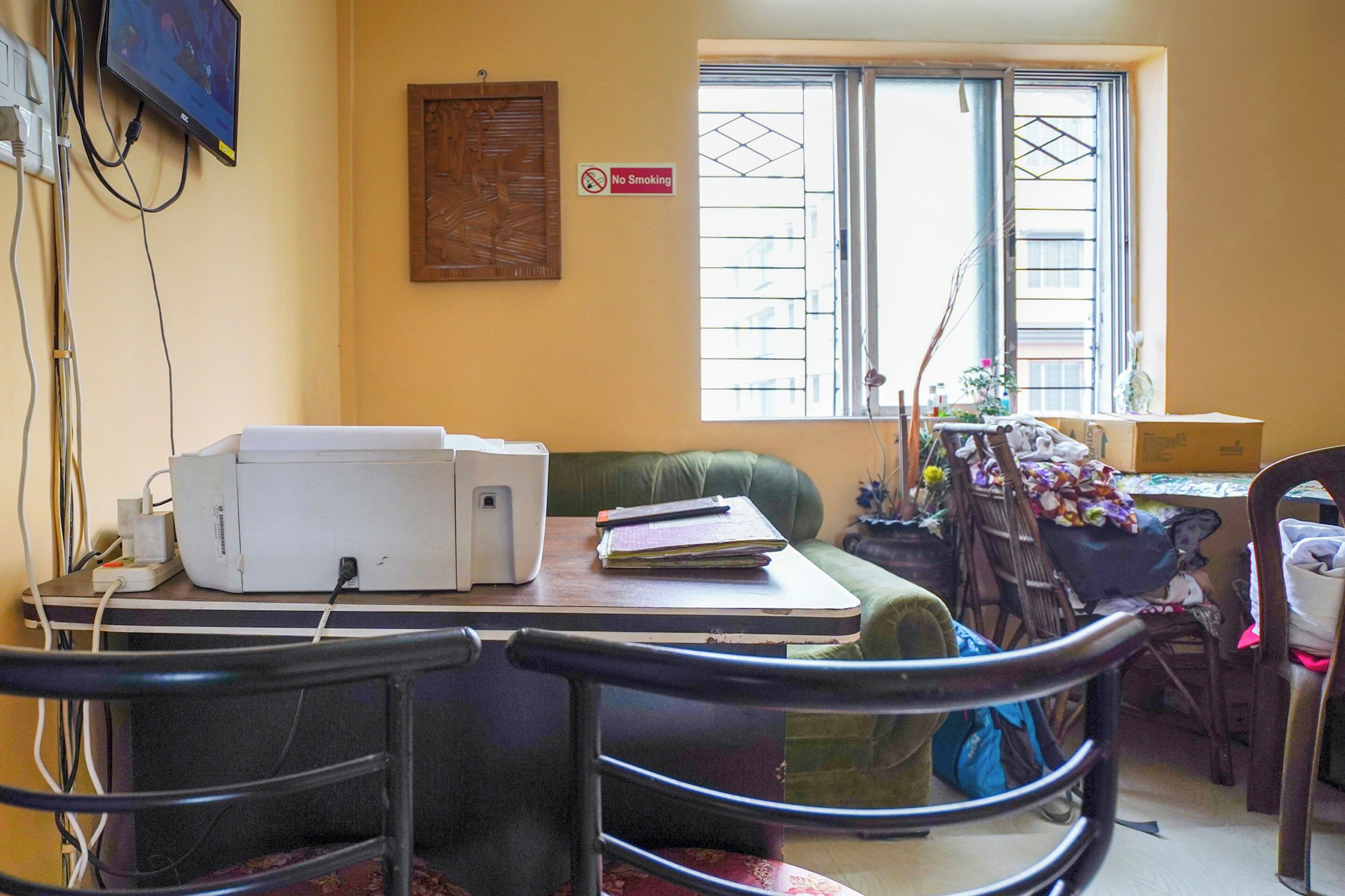 A room with a desk, a chair, a window with a view, a 'No Smoking' sign, and some cables.