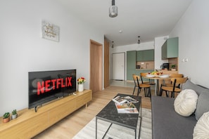 A modern living room with a flat-screen TV, a dining area, and a kitchen. - Lumina 2-room Apt w/ Parking I Balcony (Warszawa)