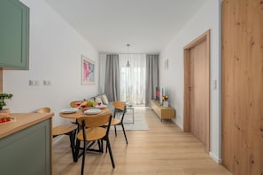 A modern dining area with a wooden table, chairs, and a view of a living room. - Lumina 2-room Apt w/ Parking I Balcony (Warszawa)