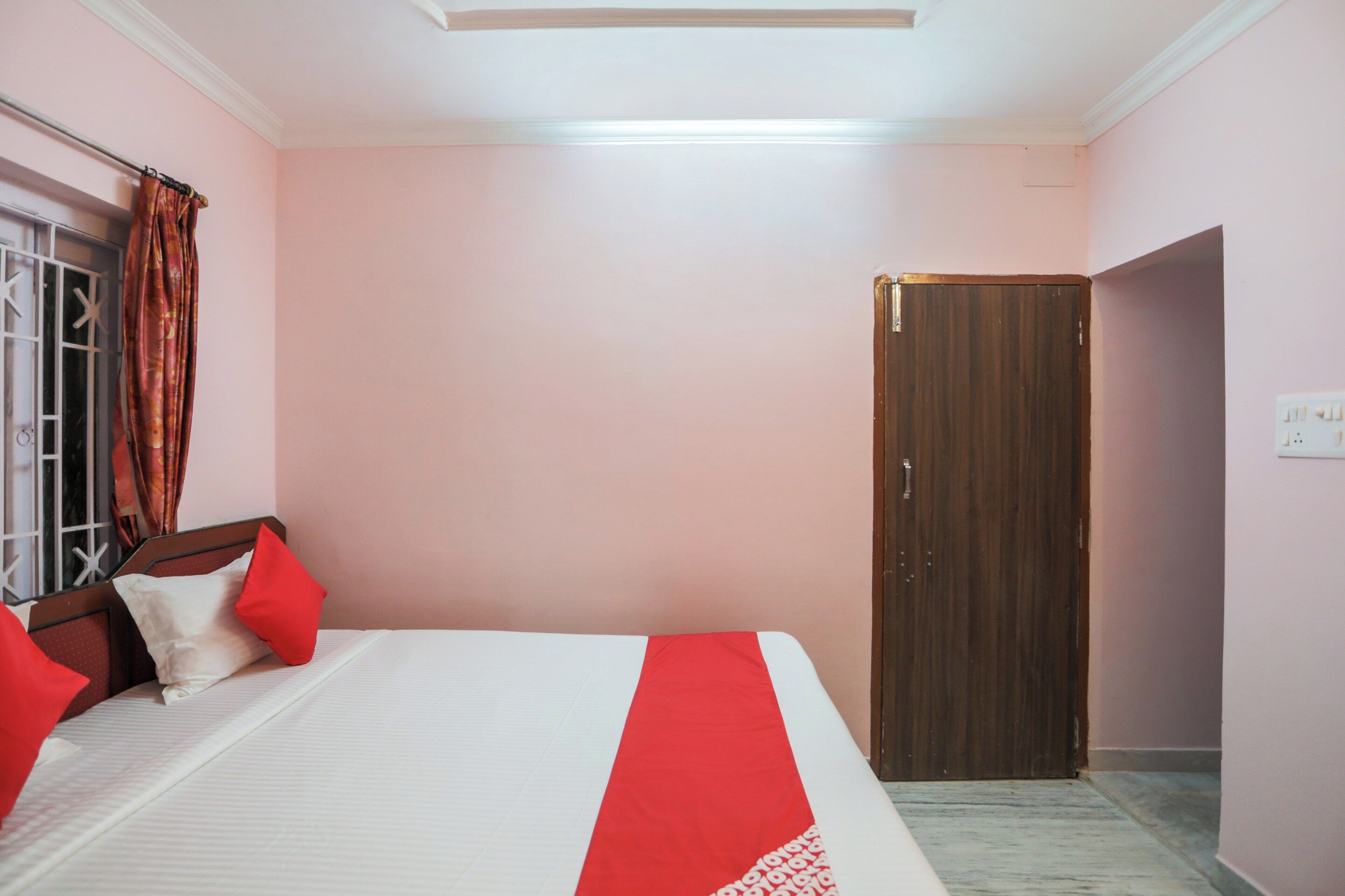 Un dormitorio con cama, una puerta de madera y una ventana con cortinas.