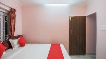 Un dormitorio con cama, una puerta de madera y una ventana con cortinas.