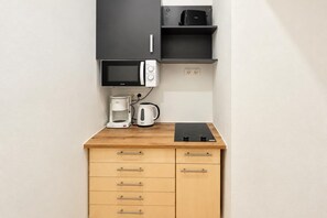 A kitchenette with a microwave, coffee maker, and a black induction cooktop on a wooden countertop. - Six Tickets to Vienna 2BR near Westbahnhof (Vienna)