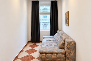 A room with a patterned floor, a sofa, a window with curtains, and a painting on the wall. - Six Tickets to Vienna 2BR near Westbahnhof (Vienna)