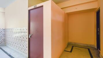 A corridor with a closed door, tiled walls, and a tiled floor.