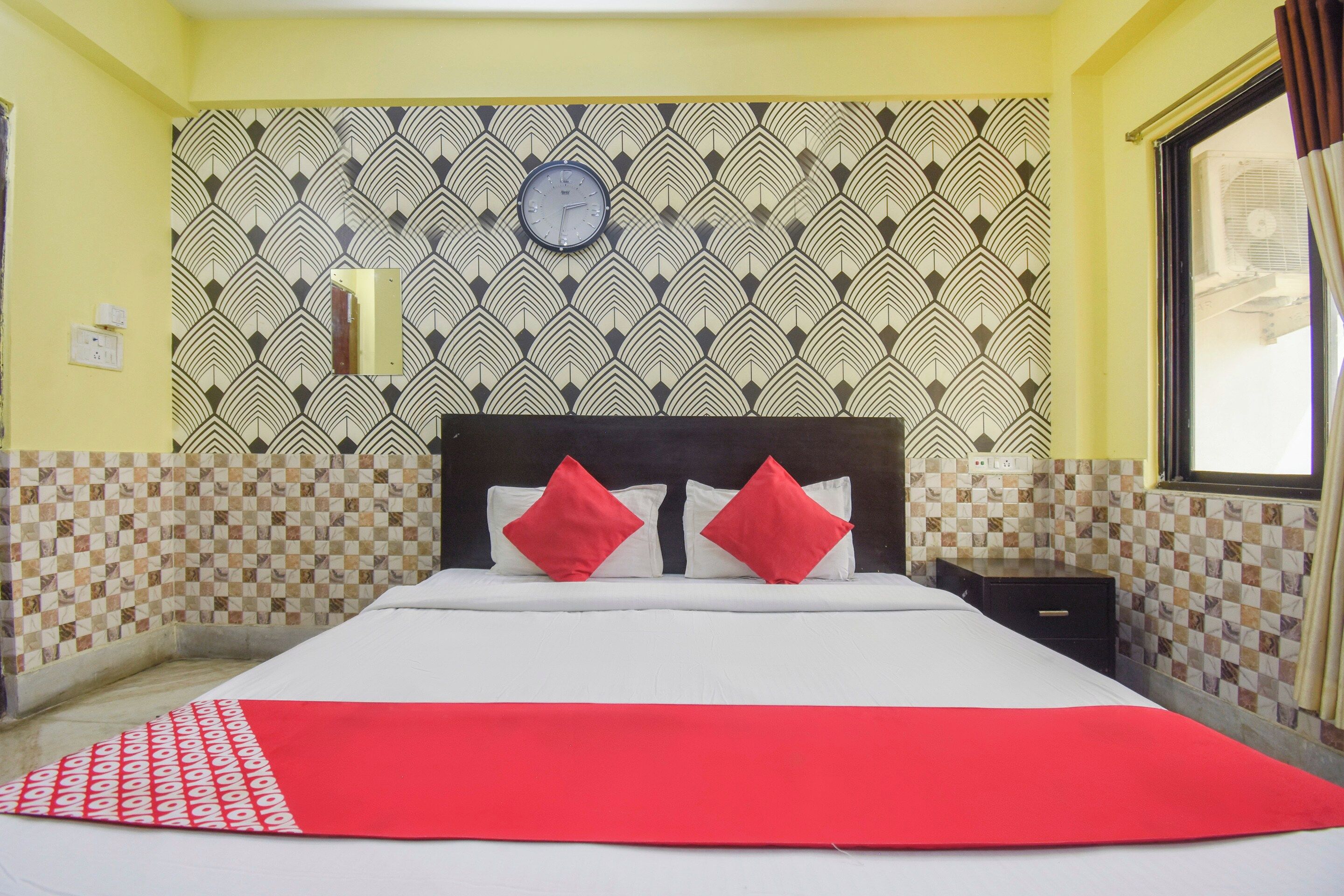 A hotel room with a bed, a clock on the wall, and patterned wallpaper.