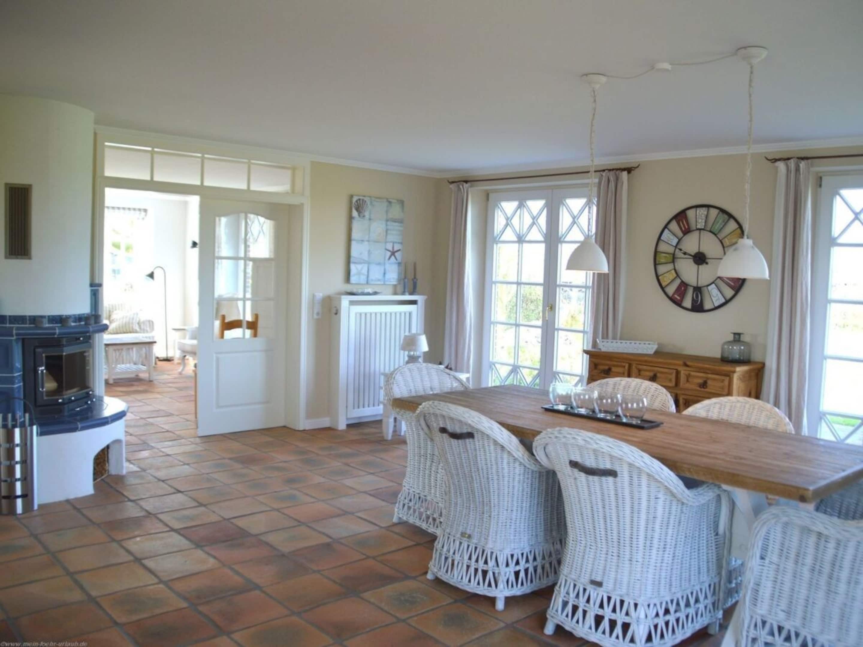 A spacious room with a fireplace, a dining table with chairs, and a large window with curtains.