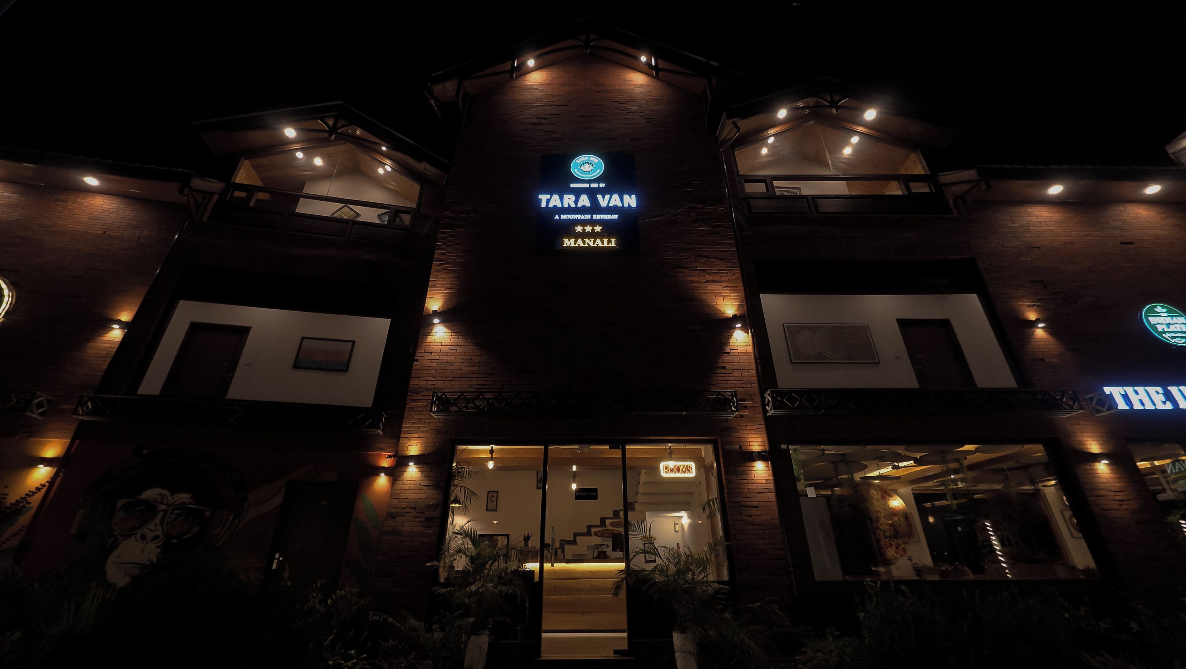 Un edificio con un letrero que dice 'TARA VAN MANALI' y 'A MOUNTAIN RETREAT', con una calificación de 5 estrellas.