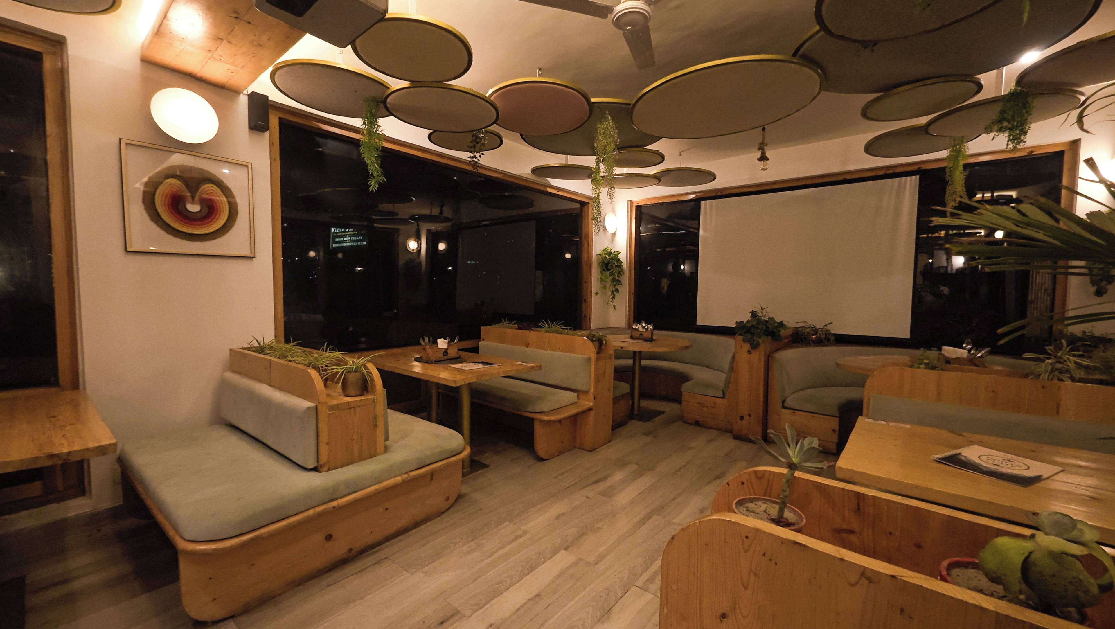 Un área de estar interior acogedora con mobiliario de madera y plantas colgantes.