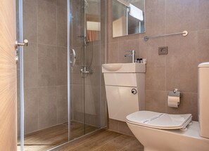 Un bagno con doccia vetro, WC bianco e lavabo con specchio sopra.