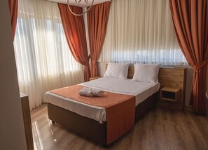 Una camera da letto con un letto, tende, un comodino e un pavimento in legno.