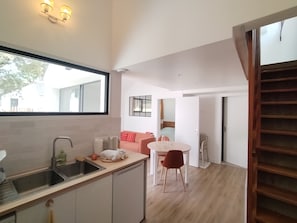 A modern kitchen with a sink, countertop, and a dining area with a table and chairs. - New Listing (Meschers-sur-Gironde)