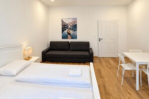 A bedroom with a bed, a sofa, a dining table, and a chair. - Drop Your Bags Discover Vienna near Westbahnhof (Vienna)
