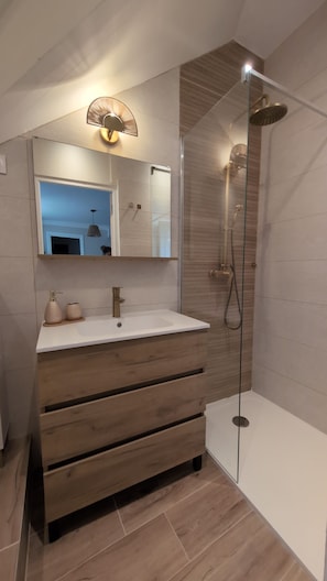 A modern bathroom with a vanity, a mirror, a shower, and a glass-enclosed shower area. - New Listing (Annonay)