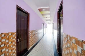 Un pasillo con puertas, paredes con diseño y piso de baldosas.
