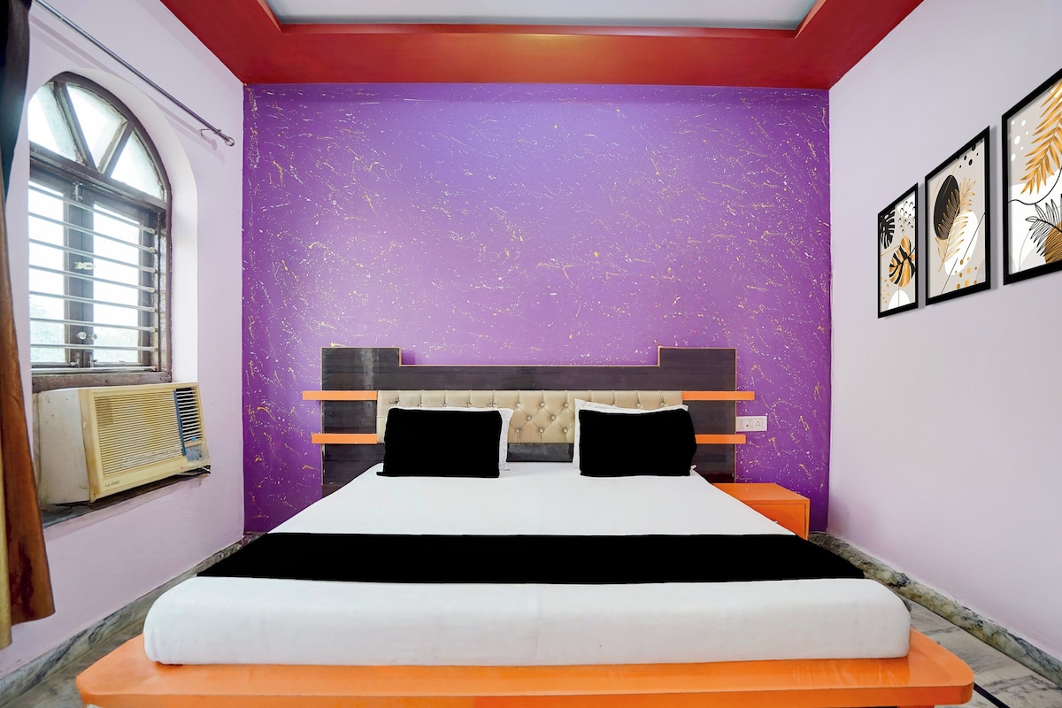A bedroom with a bed, a window, and a wall with a purple textured design.