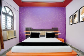 A bedroom with a bed, a window, and a wall with a purple textured design. - Hotel O Devi Kripa (Mathura)