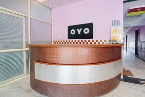 Una recepción con un letrero 'OYO', un muro con estampado y un pasillo con puertas.