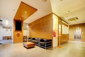 A modern lobby with a reception desk, leather seating, a decorative lamp, and an elevator. - Collection O by OYO Suncity Premiere (Mumbai)
