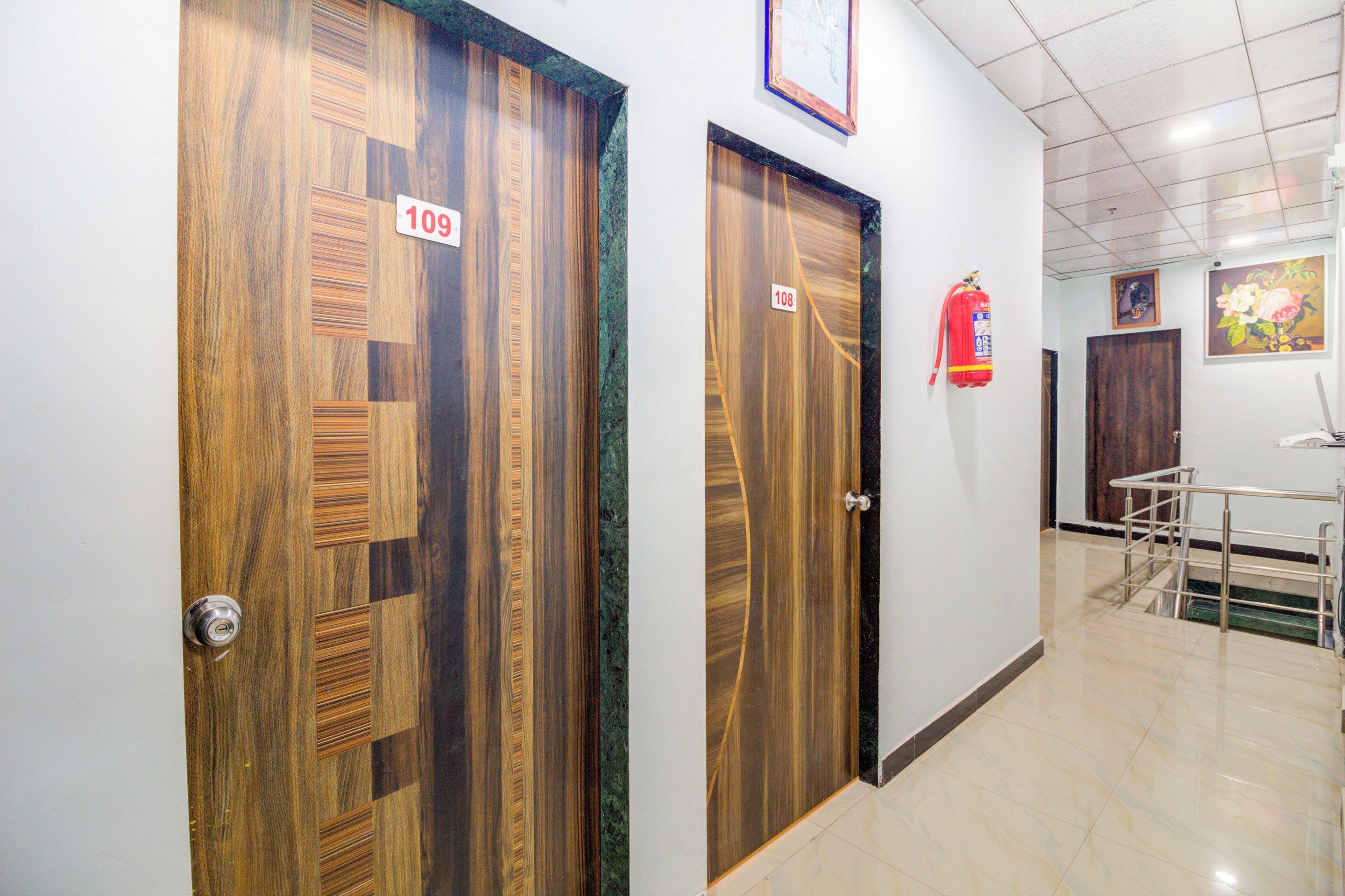 Dos puertas de madera con los números 109 y 108, un extintor y una escalera con barandilla de metal.