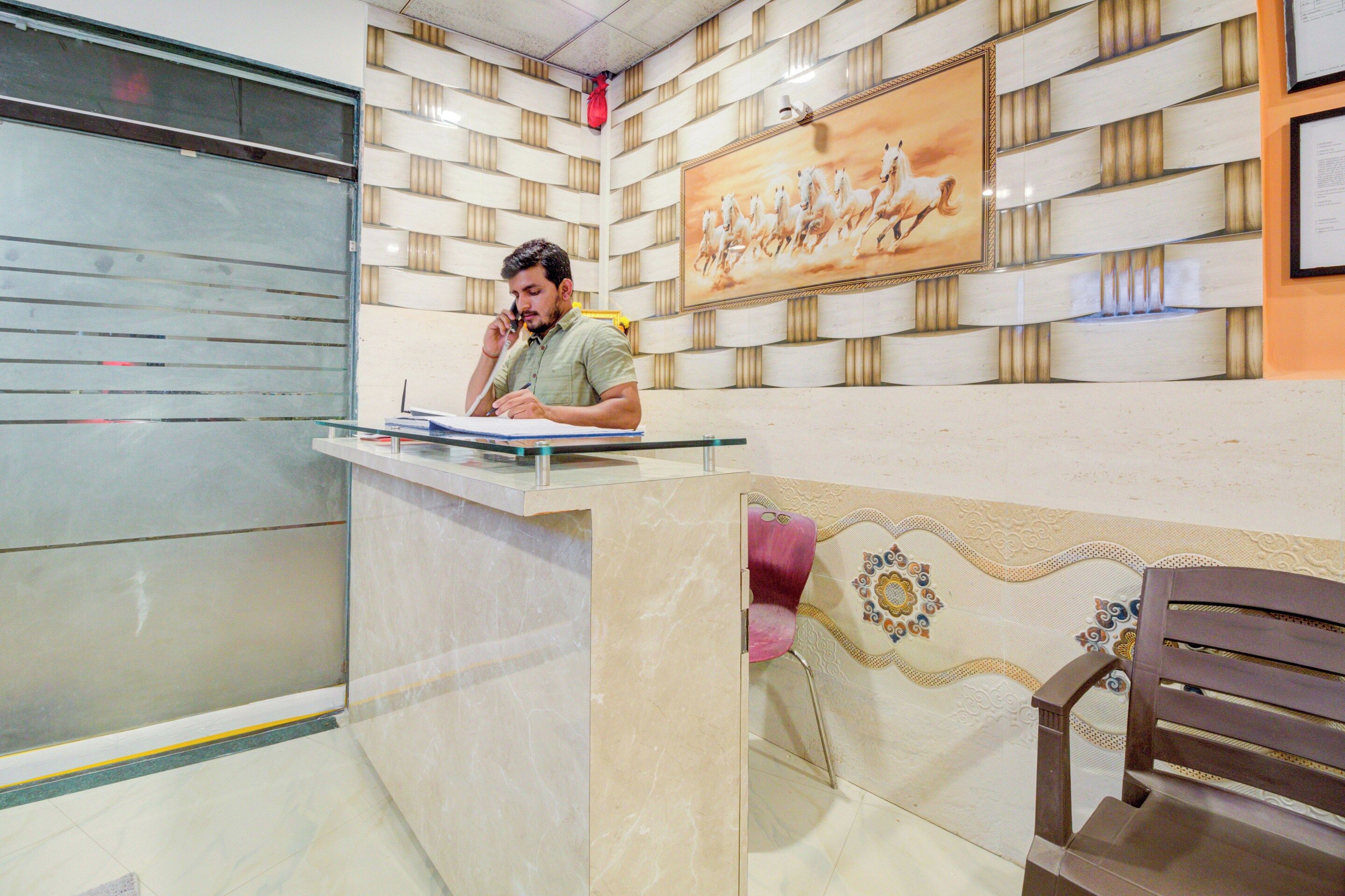 A reception area with a marble counter, a framed painting of horses, and a patterned wall.