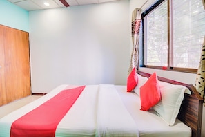 Una camera da letto con un letto, un armadio in legno e una finestra con tende.