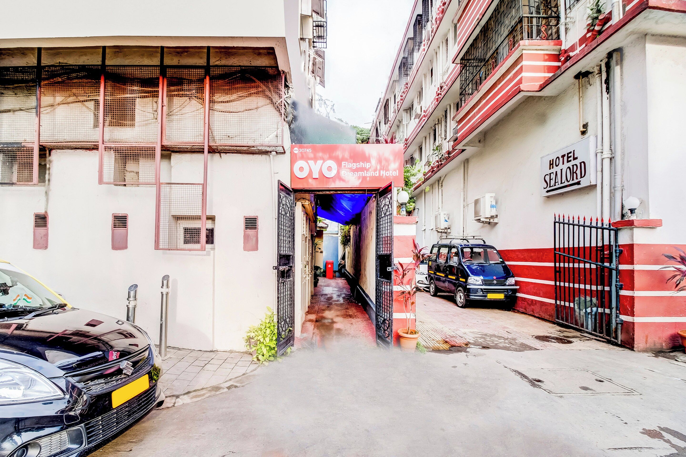 Un estrecho callejón con un hotel llamado 'OYO Flagship Dreamland Hotel' a la derecha.