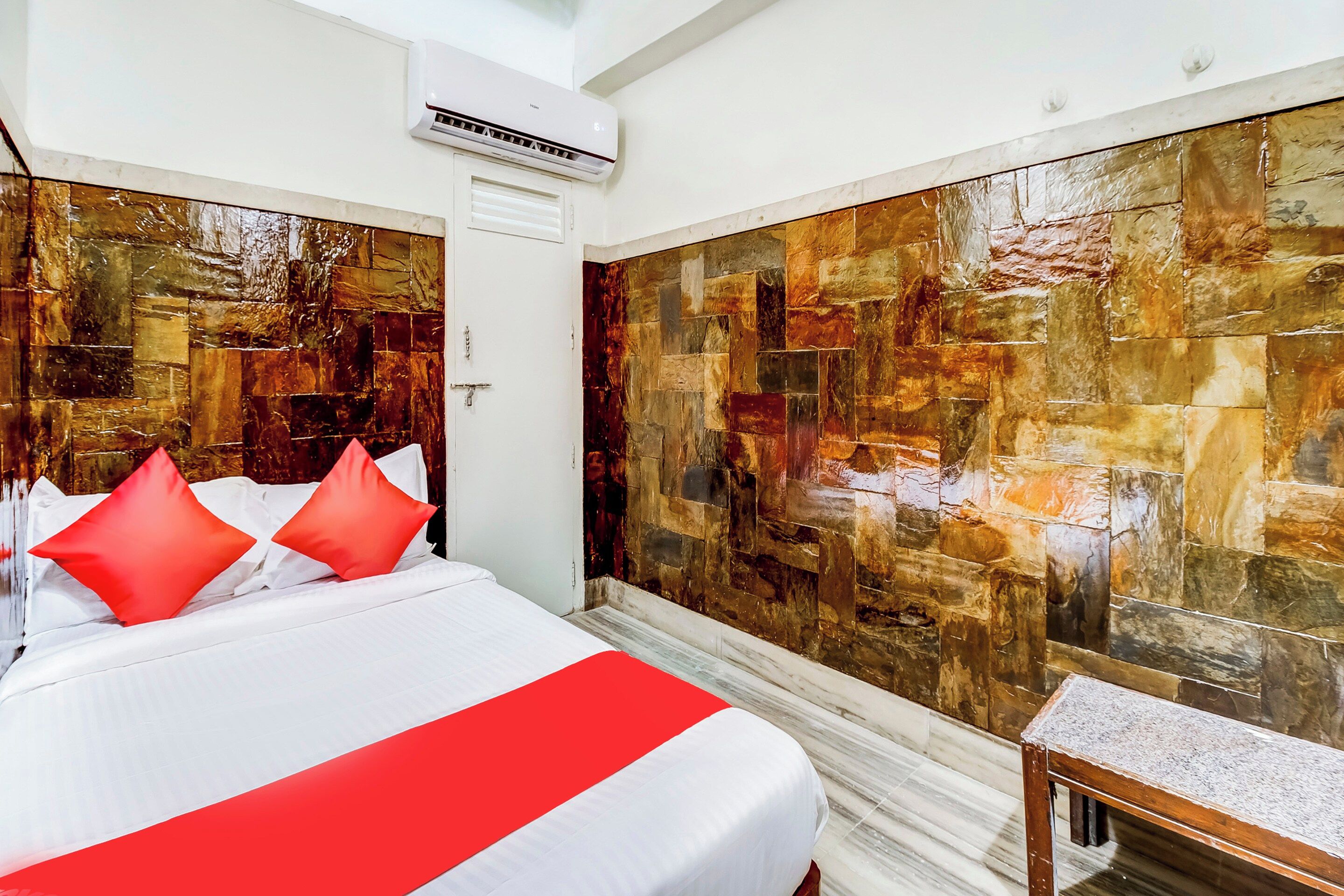 Habitación de hotel con cama, mesita de noche, aire acondicionado instalado en la pared y pared con textura.