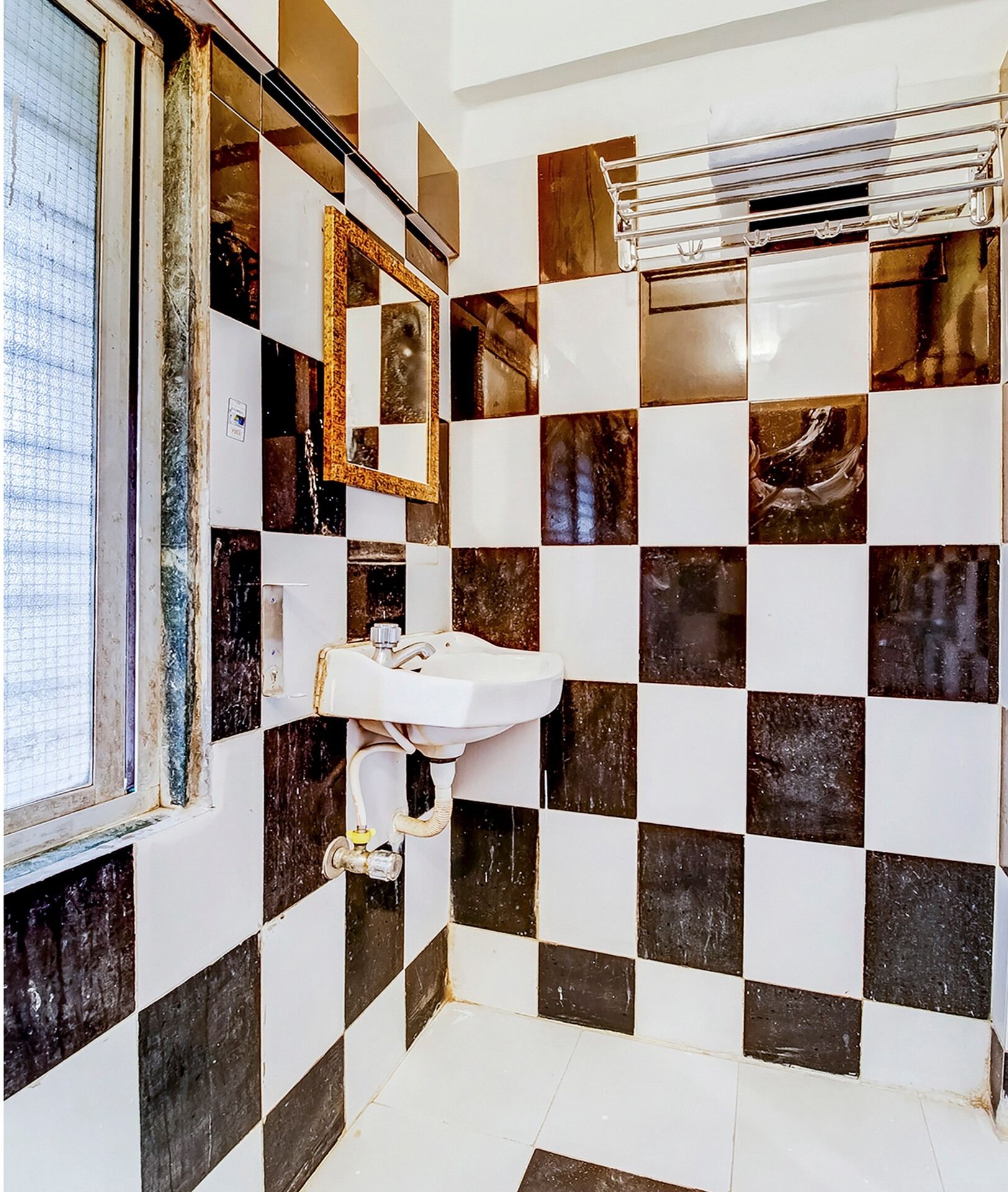 Un baño con suelo de baldosas a cuadros, un lavabo blanco y un espejo.