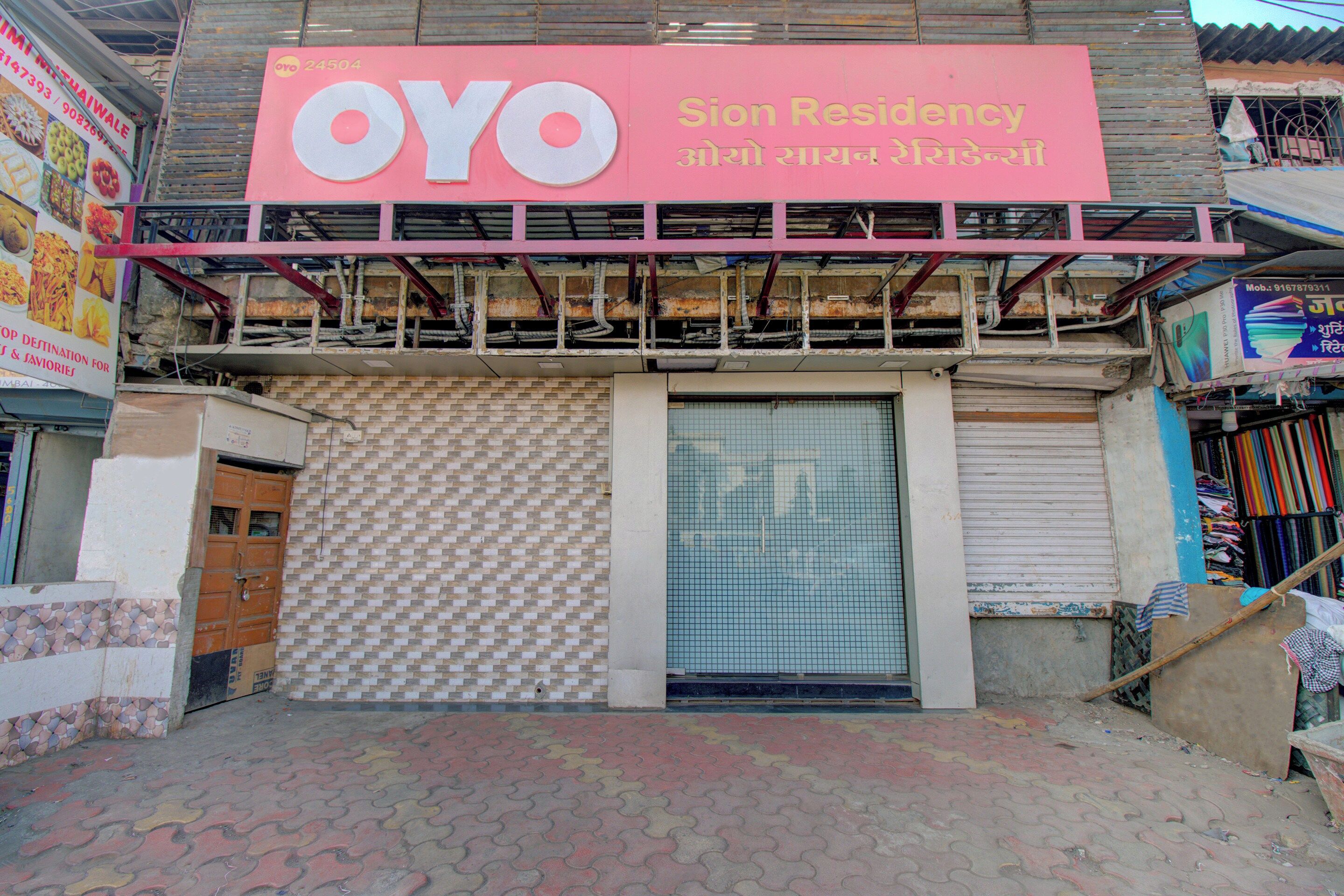 A building with a sign for 'OYO Sion Residency' and a closed shutter door.