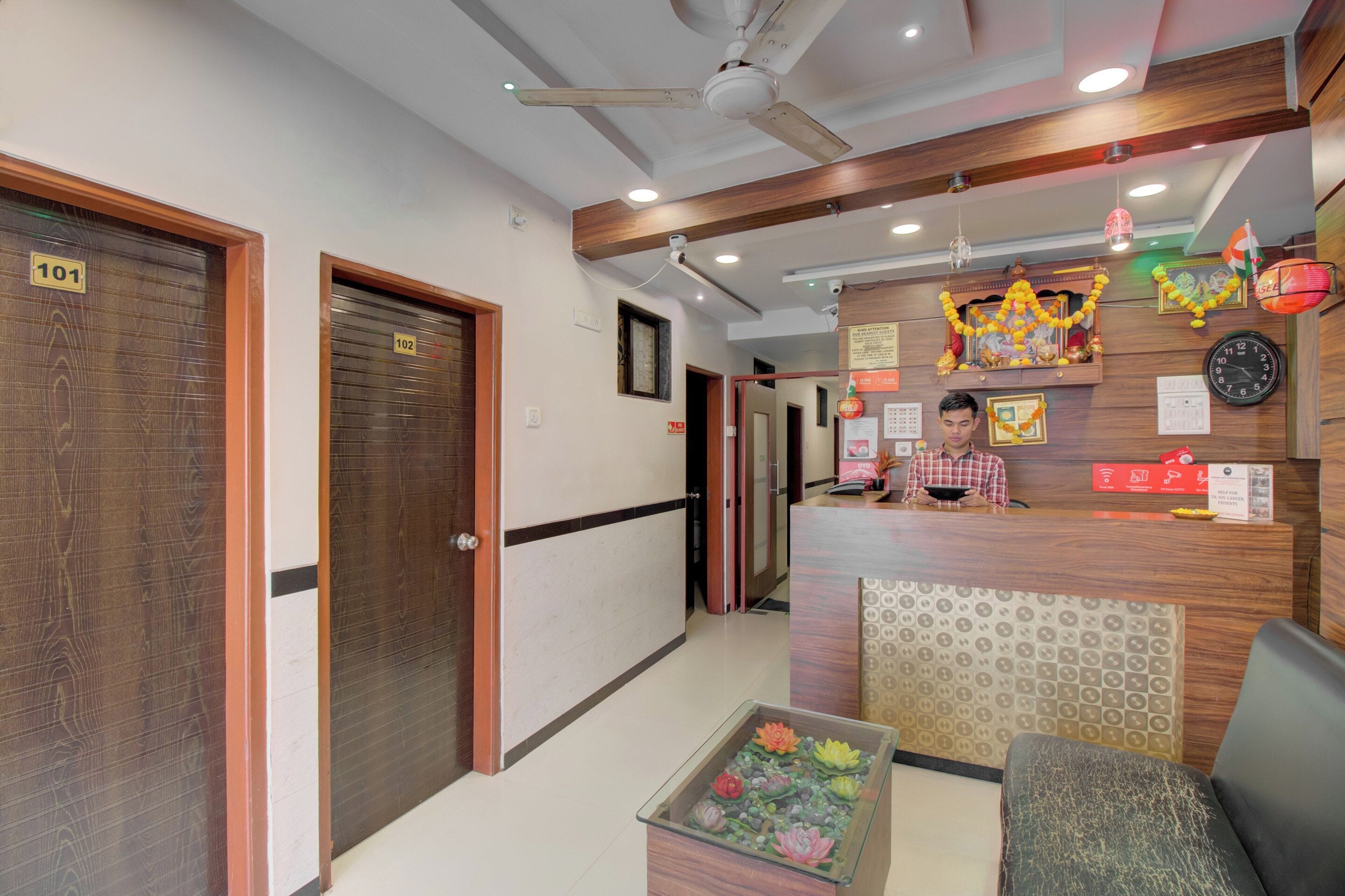 A hotel reception area with a reception desk, a clock, and a decorative wall.