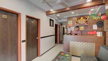 A hotel reception area with a reception desk, a clock, and a decorative wall.