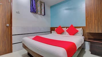 Un dormitorio con cama, armario de madera, mesita de noche y un interruptor de luz en la pared.