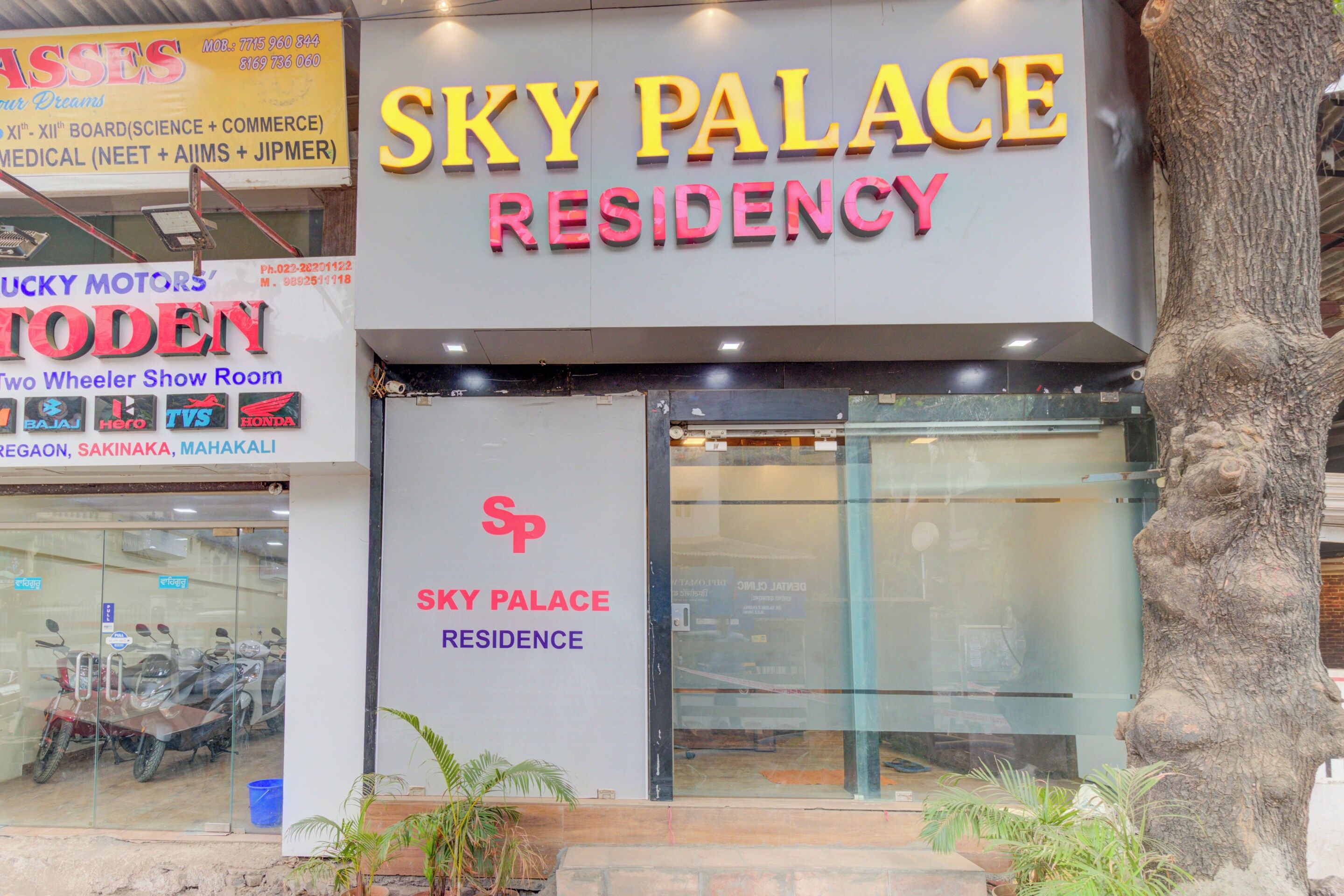 A building with a sign for 'Sky Palace Residency' and another sign for 'Lucky Motors.'