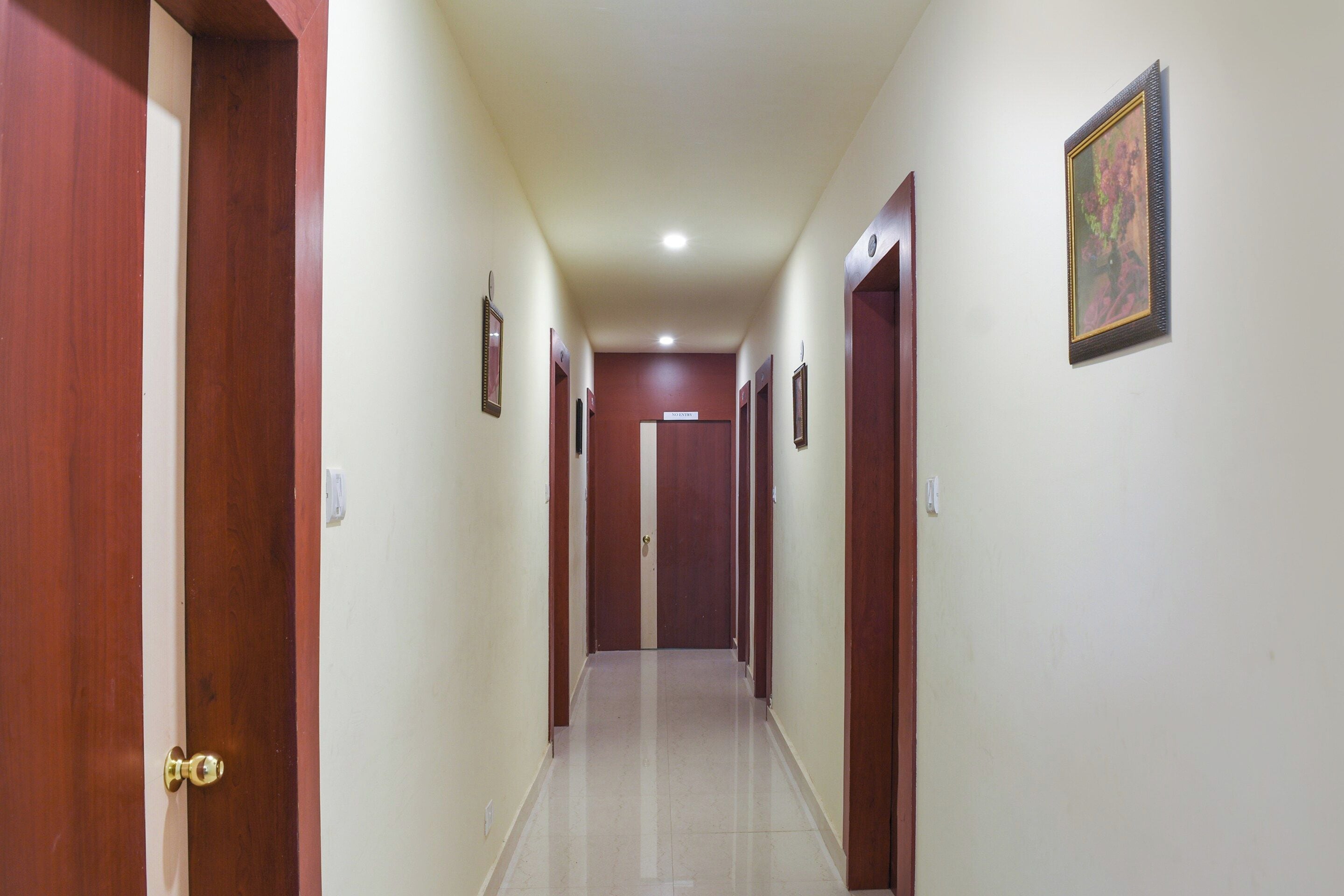 A hallway with doors on both sides, a tiled floor, and a sign indicating 'NO ENTRY' at the end.