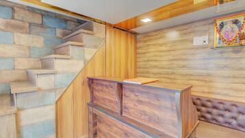 A staircase with a wooden finish, a reception desk, and a wall with a patterned design.