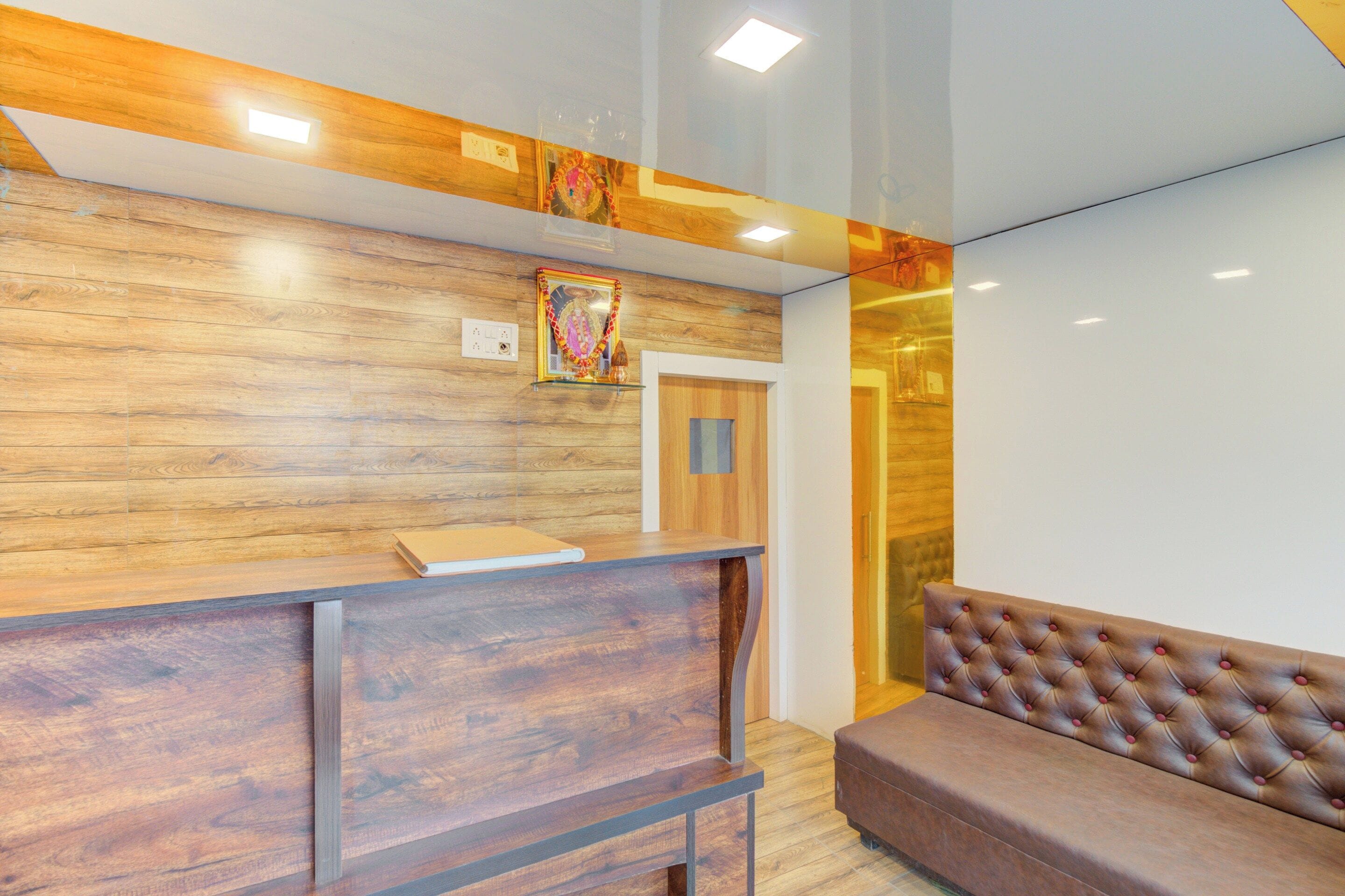 Un espace d’accueil comprenant un comptoir de réception en bois, un banc rembourré et une porte donnant sur une autre pièce.