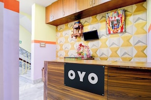 En receptionsdisk med en skylt som visar texten ”OYO” och en vägg med geometriska mönster.