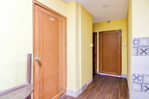 A hallway with wooden doors, yellow walls, and patterned floor tiles. - Hotel O Three Sixty Five Inn Guest House (Barasat)