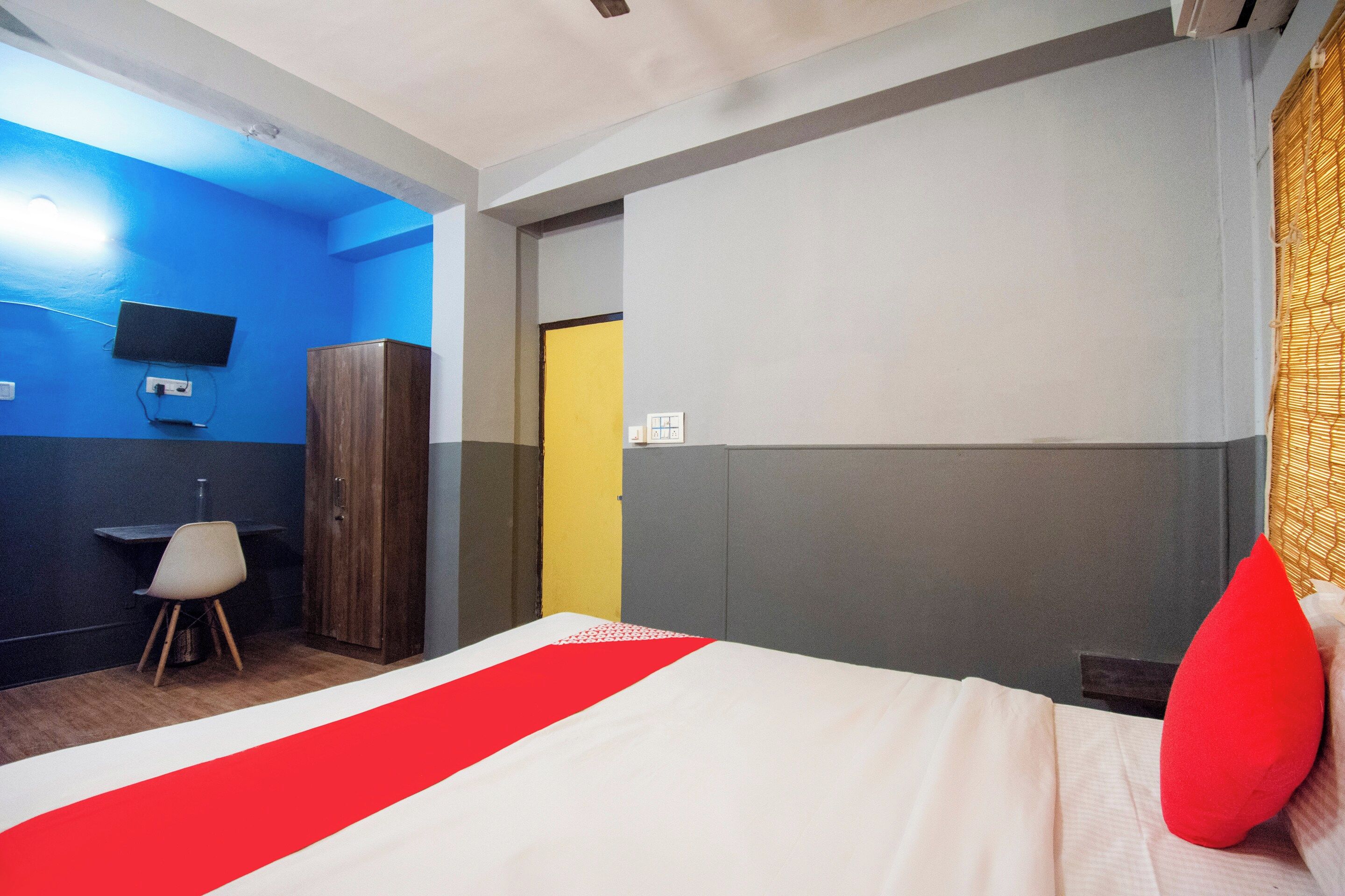 A hotel room with a bed, a desk, a chair, and a wardrobe.