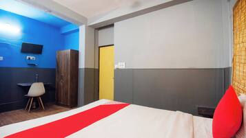 A hotel room with a bed, a desk, a chair, and a wardrobe.